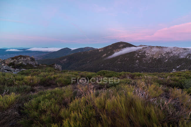 Desde arriba de la montaña poderosos picos y colorido cielo de la noche en el fondo - foto de stock