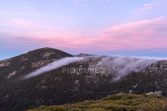 Desde arriba de la montaña poderosos picos y colorido cielo de la noche en el fondo - foto de stock