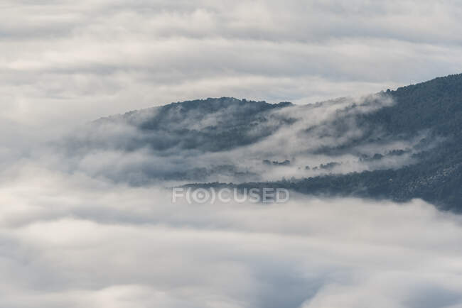 De cima de picos pretos de montanhas poderosas entre nuvens grossas brancas suaves — Fotografia de Stock