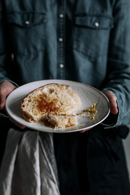 Неузнаваемая женщина показывает кусочки вкусного свежего бриошского хлеба с коричневым джемом на тарелке — стоковое фото