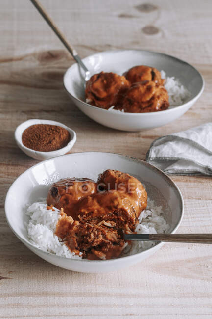 De cima tigelas de arroz e deliciosas almôndegas de lentilha com molho de caril colocado perto de especiarias e guardanapo em mesa de madeira em casa — Fotografia de Stock
