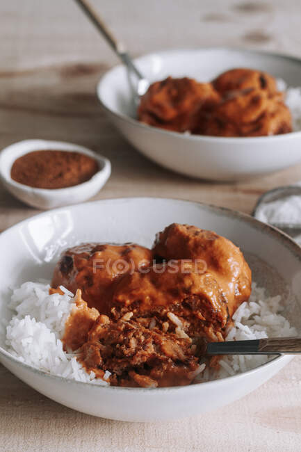 D'en haut bols de riz et de délicieuses boulettes de viande de lentilles avec sauce au curry placé près d'épices et serviette sur une table en bois à la maison — Photo de stock