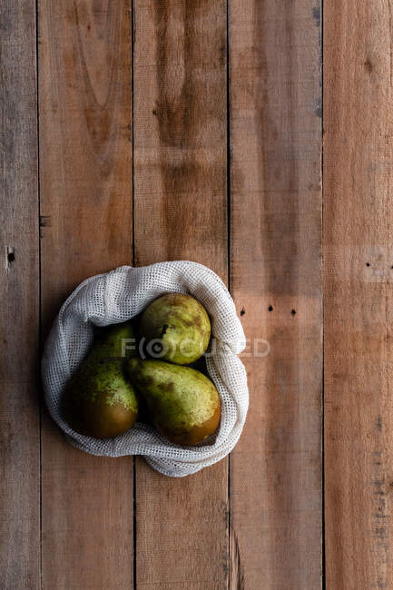 Вид зверху бавовняний мішок з соковитими свіжими грушами, розміщеними на дерев'яному столі — стокове фото