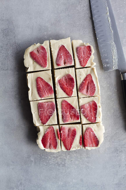 Draufsicht in Stücke geschnitten köstliche hausgemachte Frost Dessert mit weißer Sahne und Erdbeere in Scheiben geschnitten auf Marmor-Hintergrund — Stockfoto
