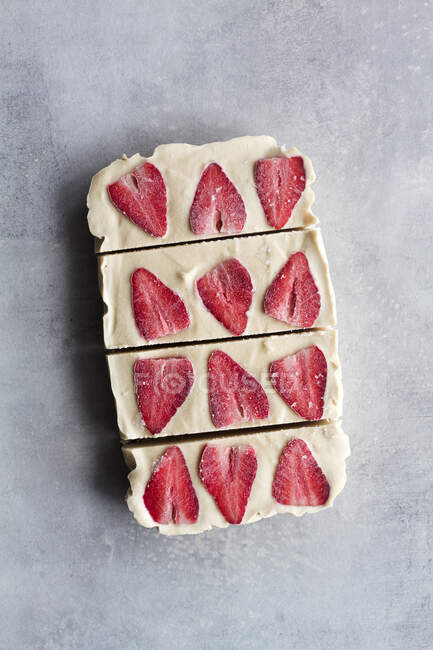 Vue du dessus de coupe en morceaux délicieux dessert glacé maison avec crème blanche et fraise tranchée sur fond de marbre — Photo de stock