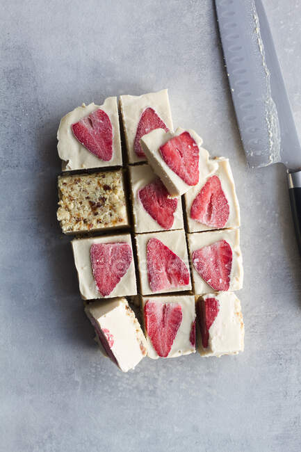 Vista superior de cortar em pedaços deliciosa sobremesa de geada caseira com creme branco e morango fatiado no fundo de mármore — Fotografia de Stock