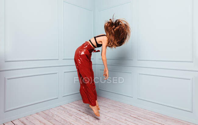Anonymous stylish dancer jumping in corner of studio — Stock Photo