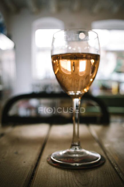 Glas Wein auf Holzbretttisch gegen Tageslicht aus Fenstern im rustikalen Restaurant — Stockfoto