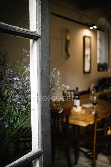Фрагмент інтер'єру сільського ресторану з дерев'яним столом, який подають з вином і сиром, видно з відкритого вікна з квітами — стокове фото