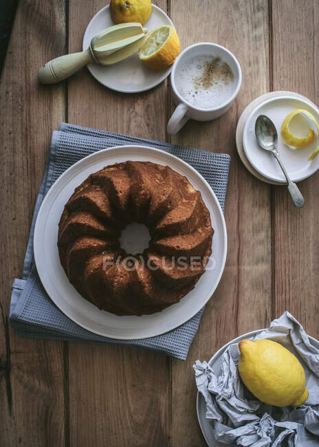 Вид зверху на смачний свіжий веганський торт з лимоном і кокосом на дерев'яному столі з інгредієнтами — стокове фото