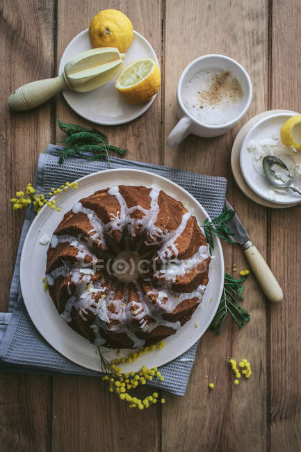 Vista superior desde arriba sabroso pastel fresco vegano con limón y coco cubierto con esmalte en la mesa de madera con ingredientes - foto de stock