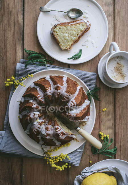 Vista superior de cima saboroso bolo vegan fresco com limão e coco coberto com esmalte em mesa de madeira com ingredientes — Fotografia de Stock