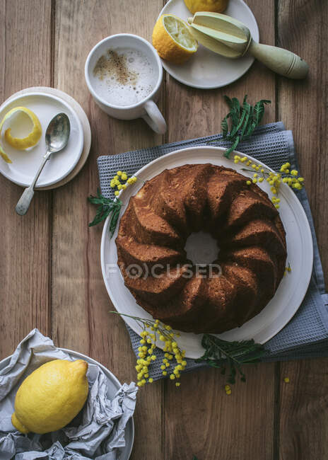 Верхний вид сверху вкусный свежий веганский торт с лимоном и кокосом на деревянном столе с ингредиентами — стоковое фото