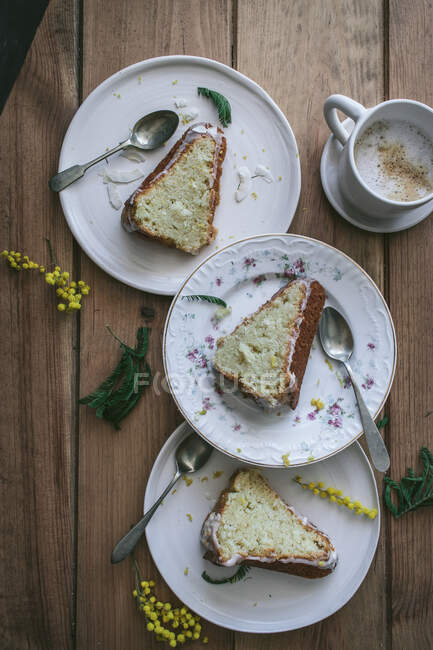 Vista superior de rodajas de limón fresco vegano y pastel de coco en platos con cucharas y taza de café - foto de stock