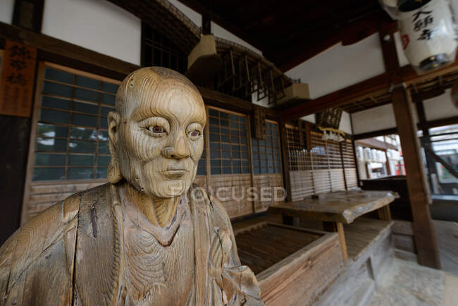 Alte geschnitzte Holzskulptur des Menschen neben traditionellem japanischen Gebäude platziert — Stockfoto