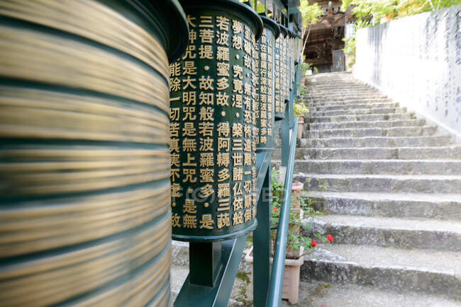 Cerca de metal verde moderno com hieróglifos construídos ao longo de escadas de pedra antigas no Japão — Fotografia de Stock