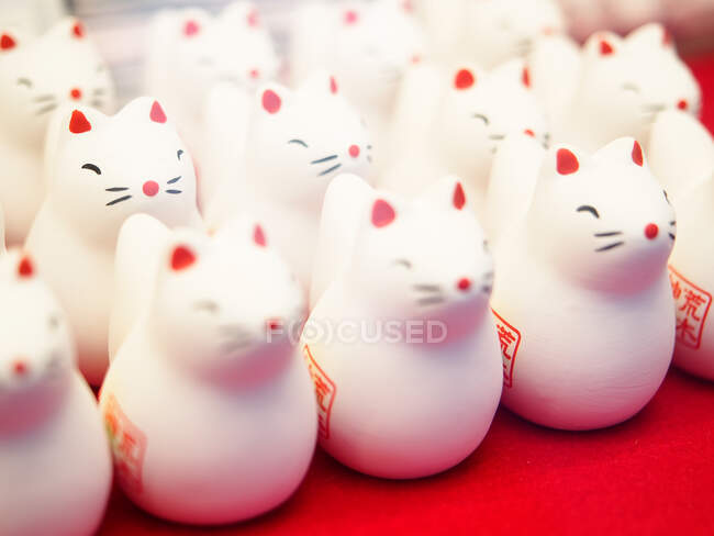 Closeup set of cute cat figurines placed on red stall in traditional Shinto shrine in Japan — Stock Photo