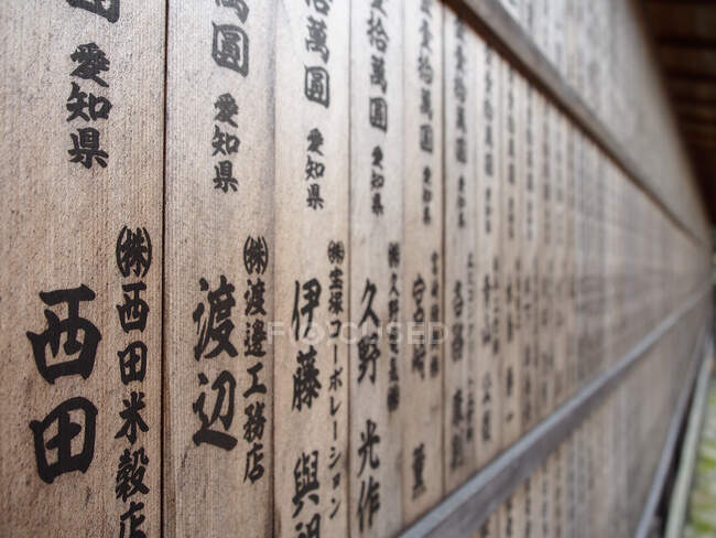 Mur de bois minable avec kanji noir situé près du sanctuaire oriental la nuit au Japon — Photo de stock