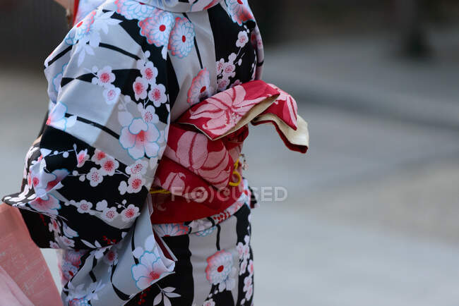 Погляд на безлику жінку в барвистому традиційному азіатському кімоно з квітами на розмитому тлі в Японії. — стокове фото