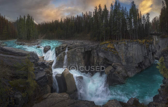 Beau paysage avec rivière de montagne coulant parmi la forêt d'épinettes vertes et une cascade puissante dans la campagne canadienne par temps nuageux — Photo de stock