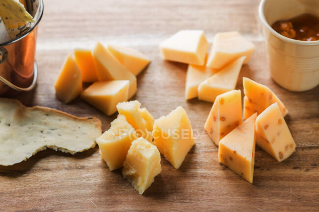 Kleine Schüssel mit würziger Soße und Käsestücken auf dem Holztisch neben knusprigen Salzstangen und Tortilla-Chips im Café — Stockfoto