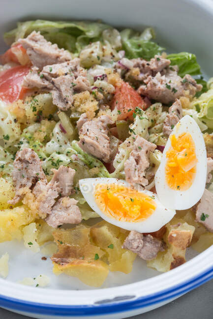 Closeup yummy tuna salad with potatoes and tomatoes mixed with egg and lettuce served in restaurant — Stock Photo
