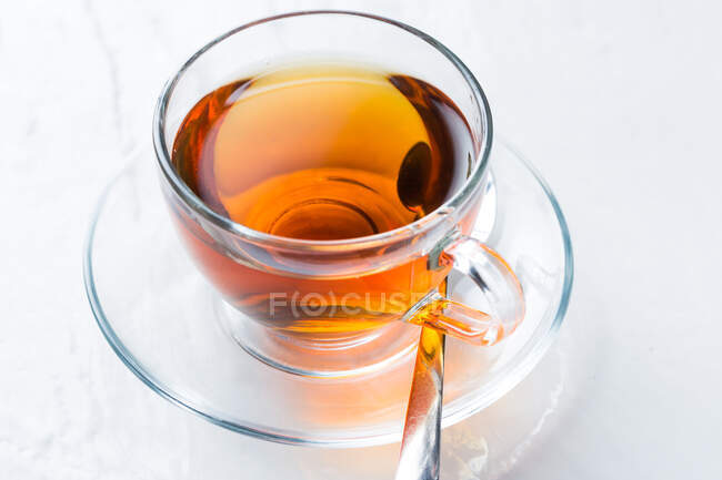 Tazza di tè caldo aromatico da primo piano posta sul piattino sul tavolo in caffetteria — Foto stock