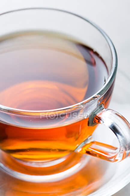 Primo piano da sopra tazza di vetro di tè caldo aromatico posto sul piattino sul tavolo in mensa — Foto stock