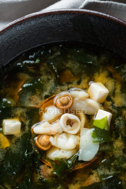 From above bowl of delectable dumpling soup with tofu and mushrooms placed on table in restaurant — Stock Photo