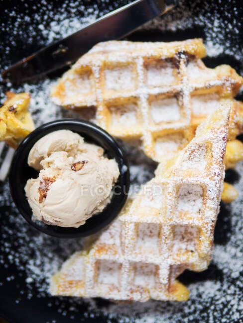 Top view of bowl with yummy ice cream ball placed on plate near sweet soft waffle in cafe — Stock Photo
