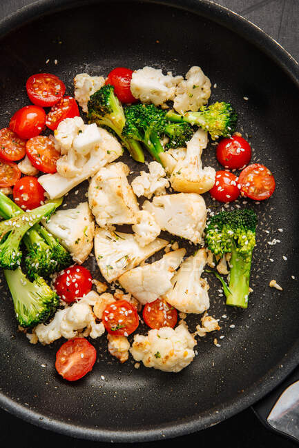 Top view of yummy cherry tomatoes with fresh cauliflower and broccoli frying on hot pan in kitchen — Stock Photo