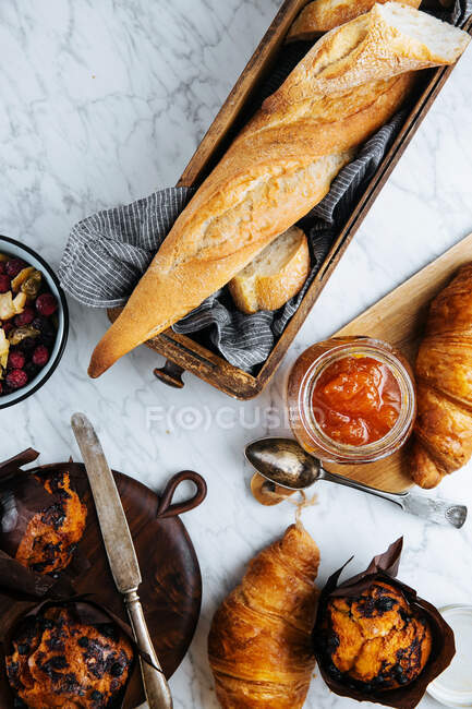 Top view composition of fresh baguette and croissants served with aromatic sweet apricot jam on marble table — Stock Photo