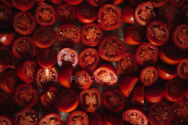Вид сверху свежих спелых помидоров красной черешни, разрезанных пополам, приготовленных для варки. — стоковое фото