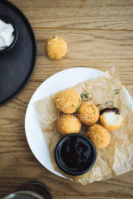 Vista superior de deliciosas bolas de batata com recheio de queijo servido com molho na placa na mesa de madeira — Fotografia de Stock