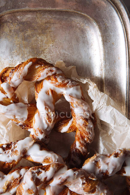 Top view closeup of yummy sweet pretzel with white sugar icing served on metal tray — Stock Photo