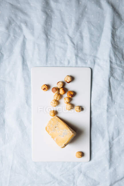 Верхний вид вкусный голубой сыр и фундук подается на белой доске на мраморном столе — стоковое фото
