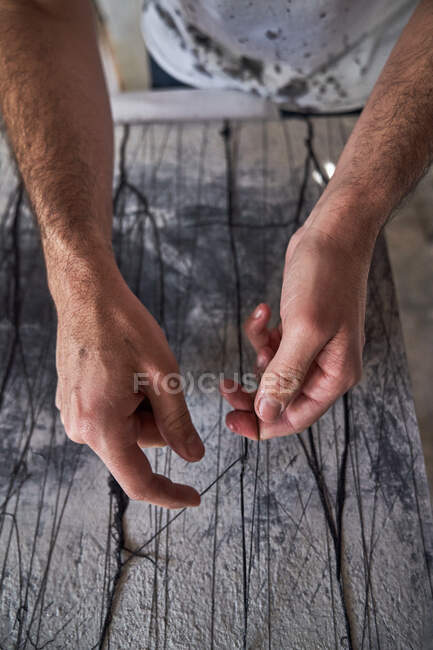 Мужчина ремесленник, работающий с нитями в мастерской — стоковое фото