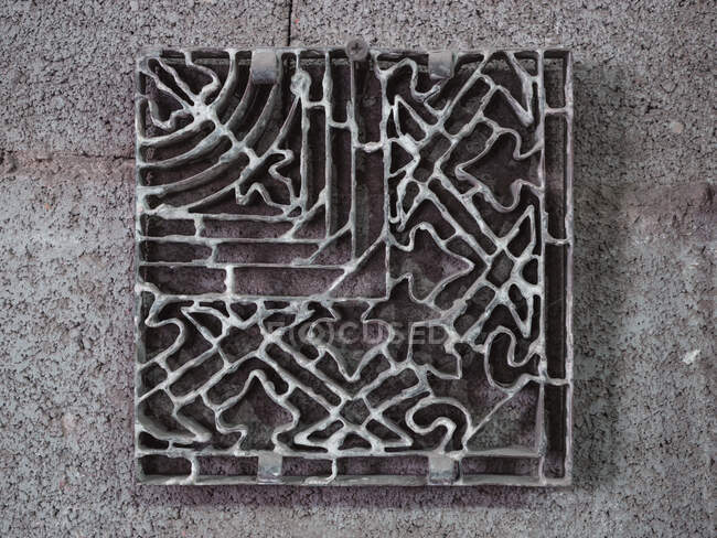 Vue du dessus du pochoir en métal décoratif carré fort carrelage sur sol en béton brut dans l'atelier — Photo de stock