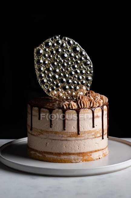 Праздничный торт с шоколадной начинкой и глазурью и серебристый изомальт украшения на столе с черным фоном — стоковое фото