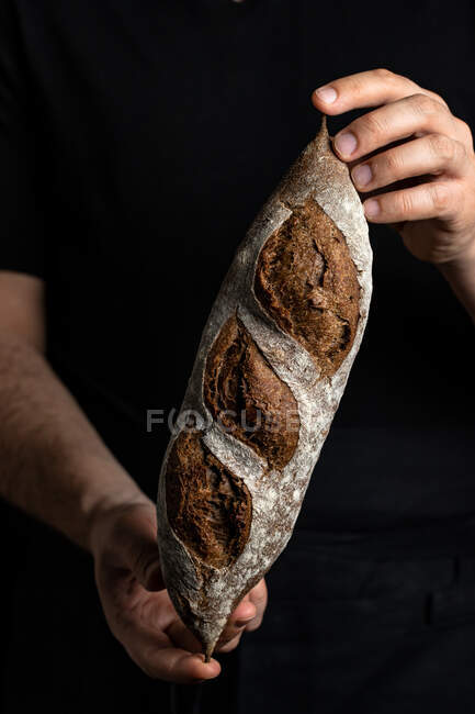 Cultivo panadero masculino en delantal sosteniendo pan artesanal fresco y saludable - foto de stock