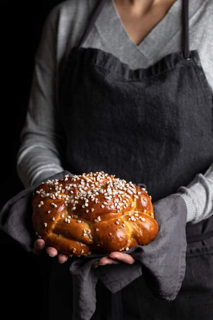 Кукурудзяна домогосподарка в фартусі, що тримає апетитний смачний домашній косиний хліб зі зморшками — стокове фото