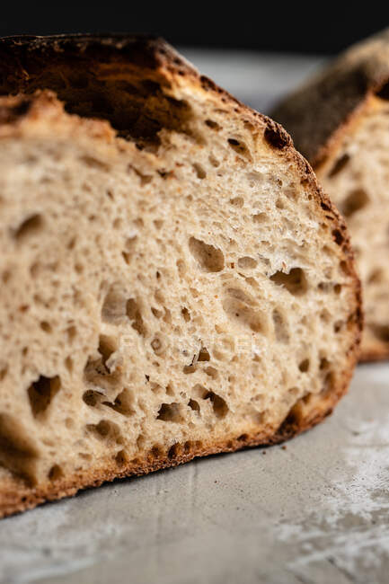 Closeup of cut fresh homemade wholegrain bread loaf with crispy crust placed on table — Stock Photo