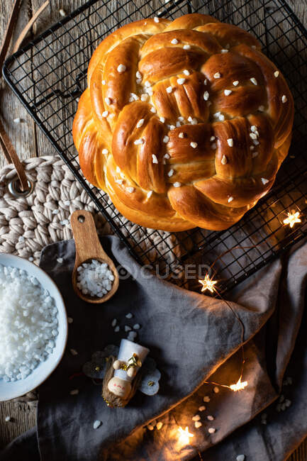 Vista superior de pão redondo trançado apetitoso fresco com polvilhas colocadas na grade de metal na mesa com elementos decorativos de Natal — Fotografia de Stock
