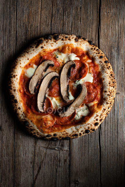 Vista superior de pizza casera con champiñones en rodajas hormiga tomates con queso sobre fondo de madera - foto de stock