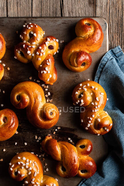 Top view of delicious homemade curly buns with raisin and sprinkles placed on wooden table — Stock Photo