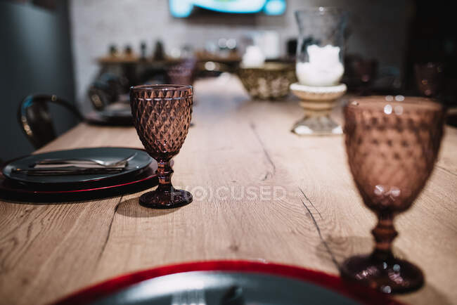 Copos de vidro colocados em mesa de madeira perto de pratos e talheres em elegante sala de banquetes em restaurante em Navarra, Espanha — Fotografia de Stock