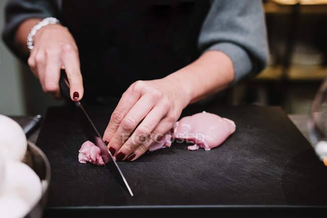 Crop person cutting chicken breast — Stock Photo
