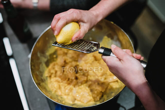 Crop person scratching lemon in kitchen — Stock Photo