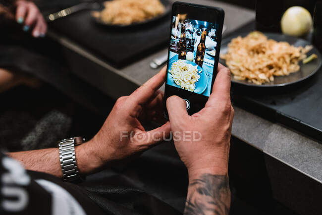 D'en haut personne méconnaissable à l'aide d'un smartphone pour prendre des photos de plats savoureux après des cours dans un atelier de cuisine en Navarre, Espagne — Photo de stock