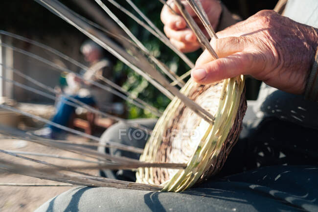 Crop senior person braiding basket — Stock Photo